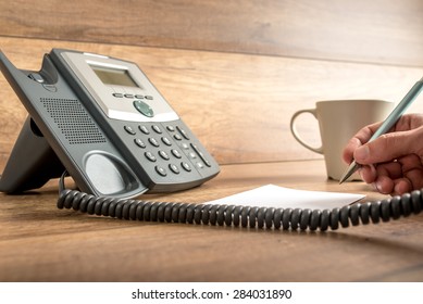 Closeup Of Male Hand Taking Important Notes As He Answers A Call On A Classical Landline Telephone. Concept Of Assistance And Secretary Work.