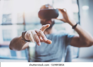 Closeup of male hand.Bearded young man wearing virtual reality goggles in modern coworking studio. Smartphone using with VR headset in office. Horizontal, blurred