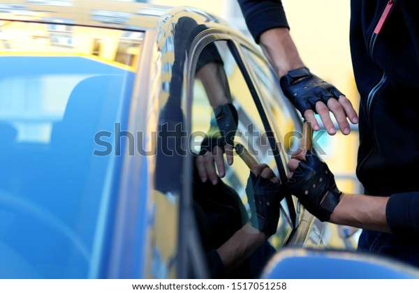 Closeup male hands in black gloves is trying to
open, break into automobile without signaling alarm. Burglar, thief
is hacking door lock of private auto. Theft in car concept. Bad
parking security.