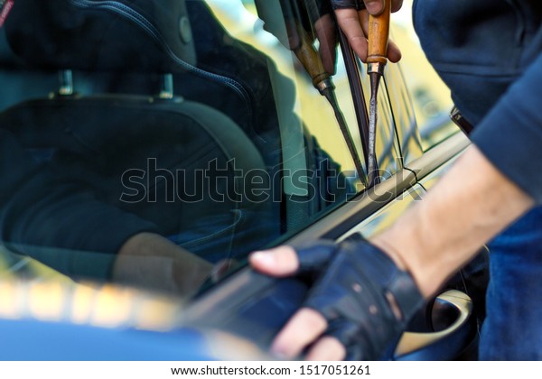 Closeup male hands in black gloves is trying to
open, break into automobile without signaling alarm. Burglar, thief
is hacking door lock of private auto. Theft in car concept. Bad
parking security.