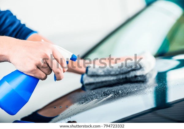 Close-up of male hands cleaning car\
with spray cleaner and microfiber towel outdoors at car\
wash