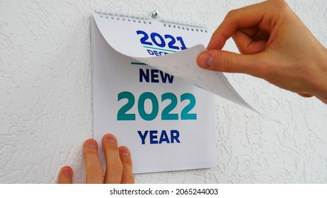 Close-up of male hands flipping through the December page of 2021 wall calendar followed by the title page of a new 2022 calendar