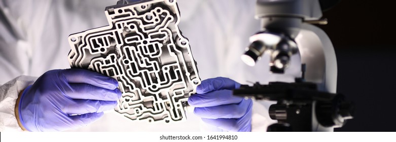 Close-up Of Male Hands Holding Metal Slushbox Hydraulic Control Labyrinth. Auto Mechanic Checking Valve Body. Microscope And Tech Tools On Workplace. Transport Technology Concept