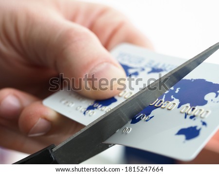 Close-up of male hands holding plastic card and cutting in half with scissors. Businessman changing bankcard with map of world and number. Accounts payable and money concept