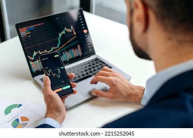 Close-up of male hands holding smartphone. Trader investor analyst using mobile phone app for cryptocurrency stock market, analyzing graph trading data index investment growth chart, plans strategy