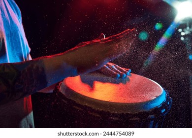 Close-up of male hands, musician playing bongo drums on dark background with stage lights. African culture live event. Concept of music, instruments, concert, sound, equipment, festival - Powered by Shutterstock