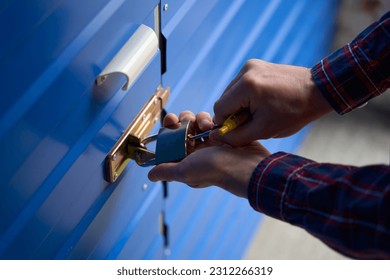 Close-up of male hands is opening the lock of self storage unit