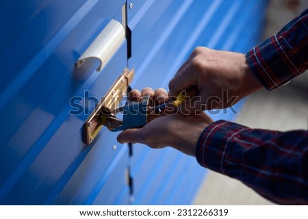 Close-up of male hands is opening the lock of self storage unit
