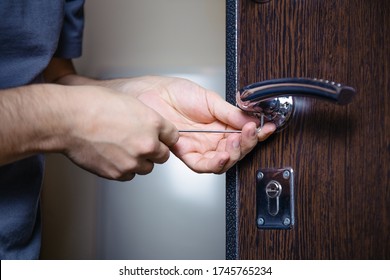 Close-up of male hands repairing or replacing an entrance door lock with a hex screwdriver. Increased house protection from burglars.