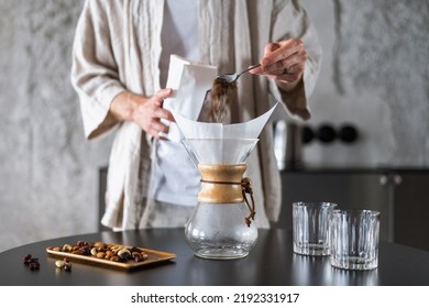 closeup of male hands with spoon prepare fresh coffee in glass chemex at kitchen room or alternative method of brewing caffeine beverage at home