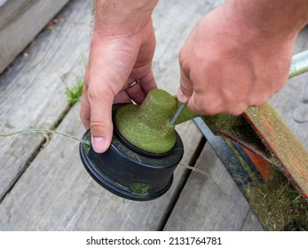 Close-up Of Male Hands That Unscrew The Nozzle With A Fishing Line On A Gasoline Trimmer. Maintenance And Repair Of Garden Equipment