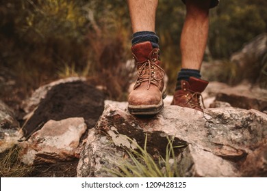 Closeup of male hikers shoes on rocky trail. Man walking through rugged path wearing trekking boots. - Powered by Shutterstock