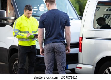 Close-up Of A Male Insurance Agent Wearing Safety Jacket Filing Report Claim Form After Accident