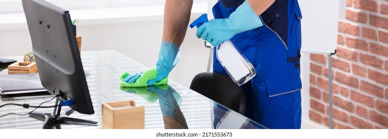 Close-up Of A Male Janitor Cleaning Desk With Cloth In Office - Powered by Shutterstock