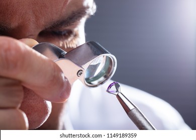 Close-up Of A Male Jeweler's Hand Looking At Diamond Through Magnifying Loupe