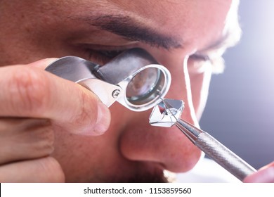 Close-up Of A Male Jeweler's Hand Looking At Diamond Through Magnifying Loupe