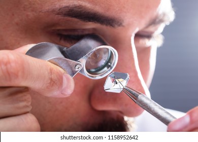 Close-up Of A Male Jeweler's Hand Looking At Diamond Through Magnifying Loupe