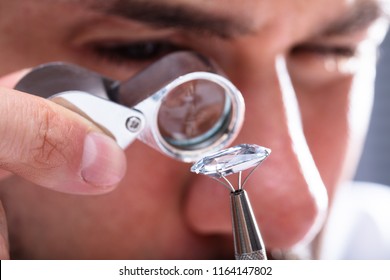 Close-up Of A Male Jeweler's Hand Looking At Diamond Through Magnifying Loupe