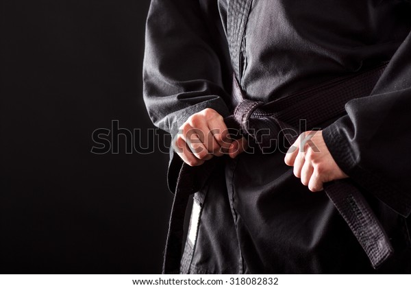 Closeup of male karate fighter tying the knot to his\
black belt