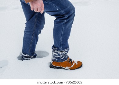 close-up of male legs in winter shoes and blue jeans walking on snow