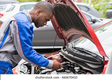 Close-up Of Male Mechanic Checking Car Battery Level With Multimeter