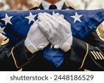 Close-up of male military soldier wearing white gloves holding a folded American flag at a memorial ceremony