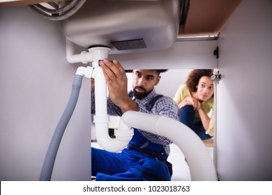 Close-up Of A Male Plumber Fixing Sink Pipe In Kitchen