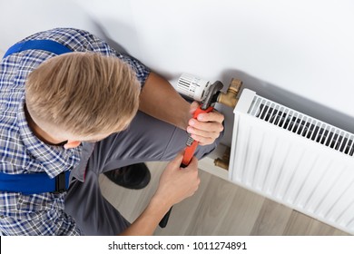 Close-up Of Male Plumber Fixing Thermostat Using Wrench At Home