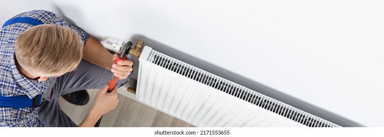 Close-up Of Male Plumber Fixing Thermostat Using Wrench At Home