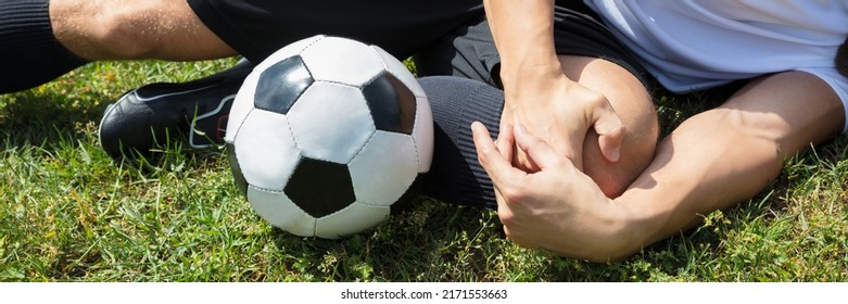 Close-up Of Male Soccer Player Suffering From Knee Injury Lying On Field