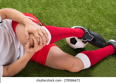 Close-up Of Male Soccer Player Suffering From Knee Injury On Field