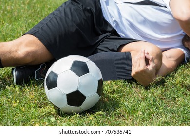 Close-up Of Male Soccer Player Suffering From Knee Injury Lying On Field