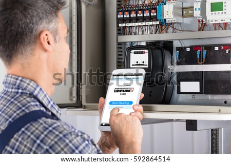 Close-up Of A Male Technician Doing Meter Reading Using Mobilephone
