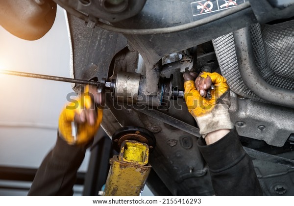 Closeup male tehnician mechanic greasy hands in\
gloves install new car oem suspensiom arm bushing during service at\
automotive workshop auto center. Vehicle safety checkup and\
maintenance concept
