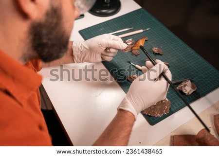 Close-up of male working at office at night restoring ancient coins, top view. Archaeological concept.