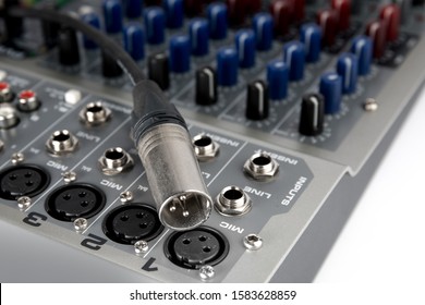 closeup of a male XLR audio connector and a female XLR jack on a sound mixing board