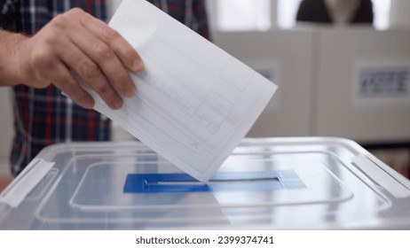 A close-up of a man about to throw a voting ballot into the sealed box during the US elections