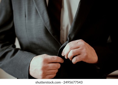 Close-up of a man adjusting his suit jacket, symbolizing confidence, professionalism, and business attire. - Powered by Shutterstock