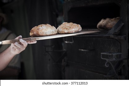 Close-up of a man baker introducing breads in a classic oven - Shutterstock ID 377112013