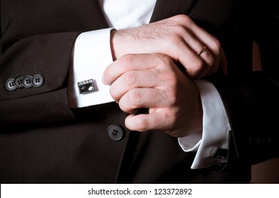 Closeup of a man in black suit correcting a sleeve - Powered by Shutterstock