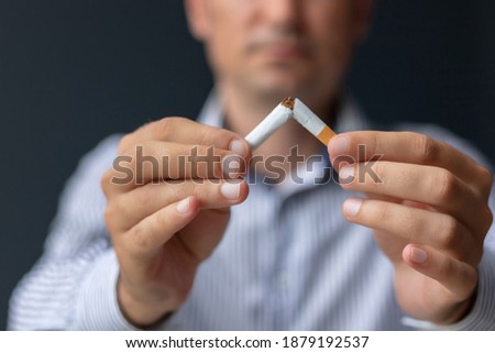 Close-up of man breaking cigarette on half while quitting smoking. Stop smoking concept. 