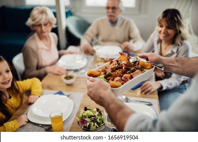 Close-up of man brining food at the table while having lunch with his family at home.  - Powered by Shutterstock