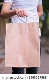 Close-up of a man with a brown paper bag standing on the street.