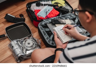 Close-up Of Man Checks The Checklist. He's Choosing Clothes, Travel Documents, The Itinerary For A Solo Trip. Travel, Holiday And Vacation Concept.