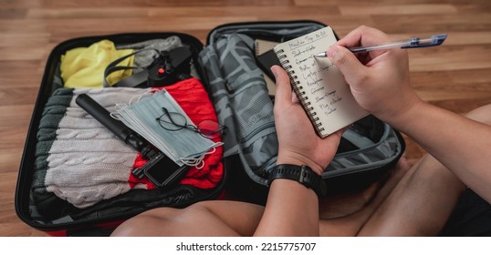 Close-up Of Man Checks The Checklist. He's Choosing Clothes, Travel Documents, The Itinerary For A Solo Trip. Travel, Holiday And Vacation Concept.
