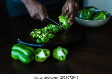 Close-up of man chopping green bell peppers on a dark surface. - Powered by Shutterstock