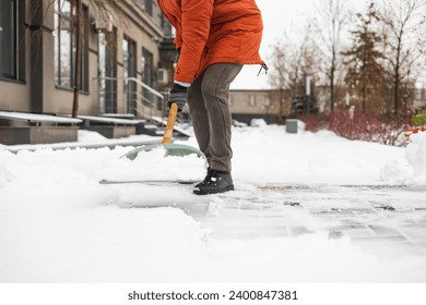 Close-up of a man cleaning and clearing snow in front of the house on a sunny and frosty day. Cleaning the street from snow on a winter day. Snowfall, and a severe snowstorm in winter. - Powered by Shutterstock