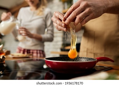 Close-up of man cracking egg in frying pan while preparing breakfast in the kitchen.  - Powered by Shutterstock