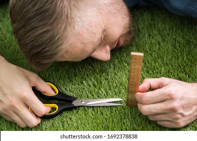 Close-up Of A Man Cutting Green Grass Measured With Ruler