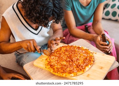 Close-up of man cutting homemade pizza to share with friends at home - Powered by Shutterstock